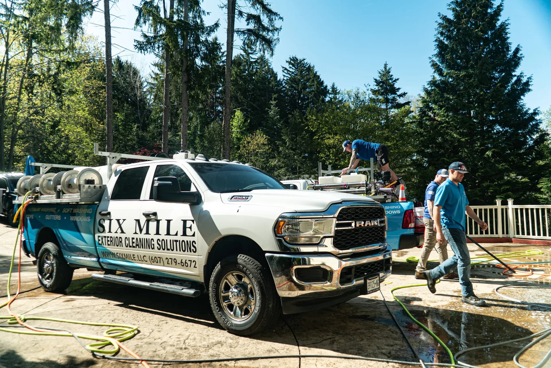 Six Mile branded truck and crew pressure washing a driveway on an Ithaca-area job