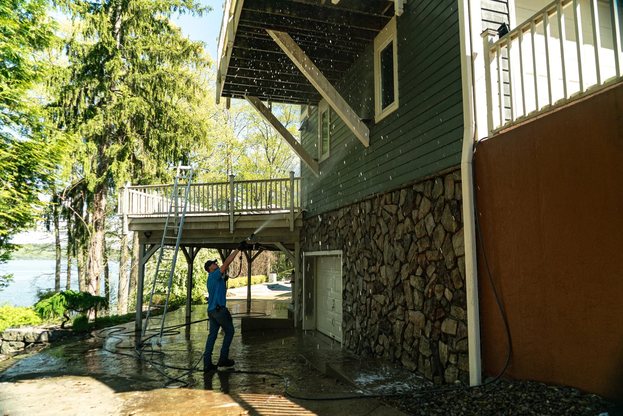 Six Mile crew soft washing a lakefront deck and stone foundation in Skaneateles
