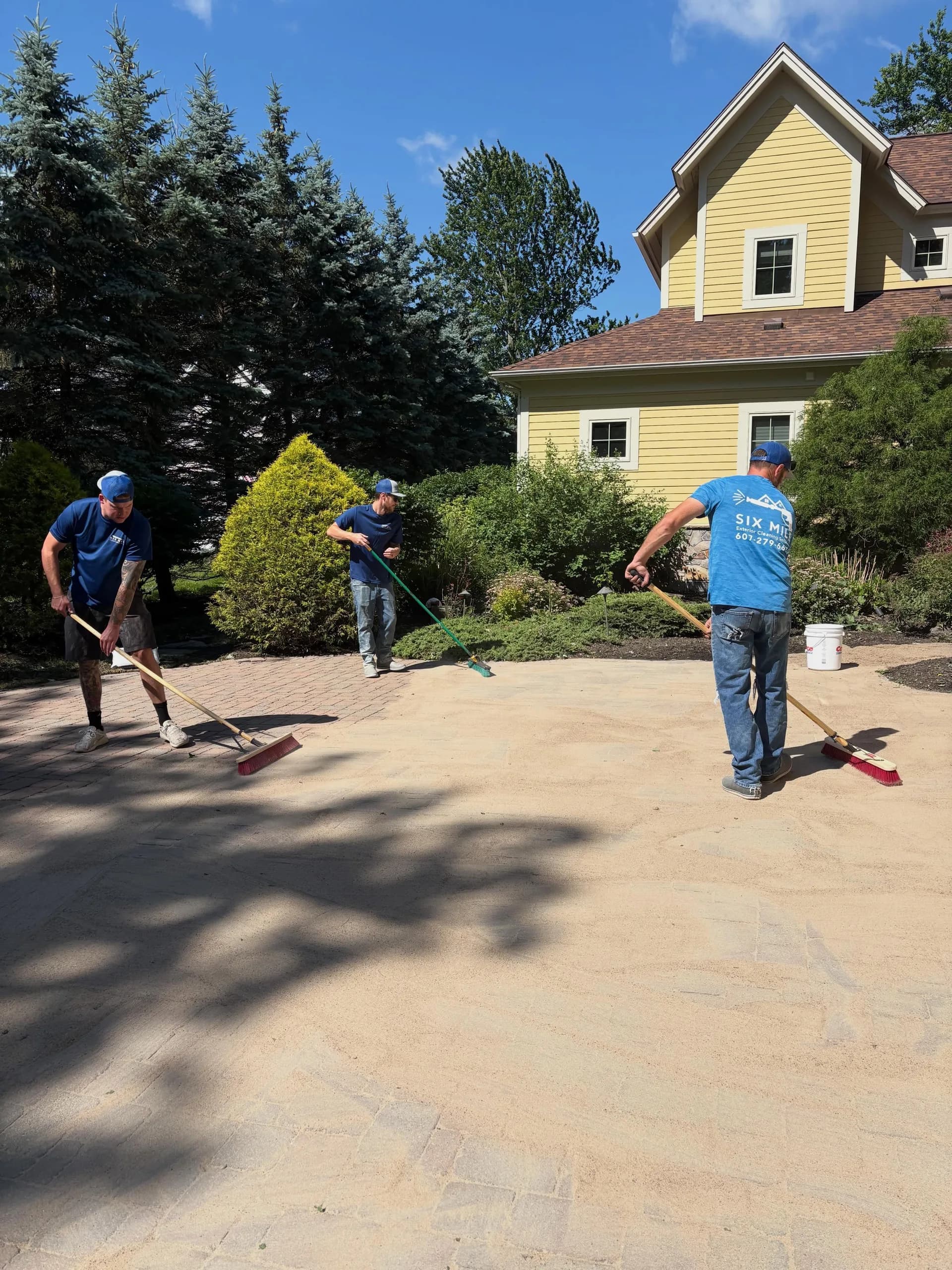 Six Mile crew broadcasting polymeric sand onto a restored paver patio