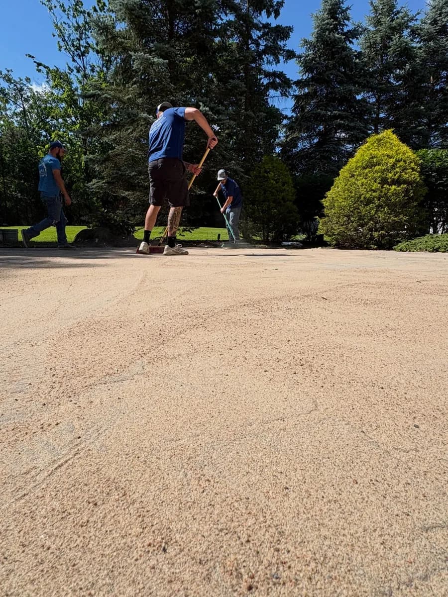 Six Mile crew broadcasting and brushing polymeric sand into paver joints
