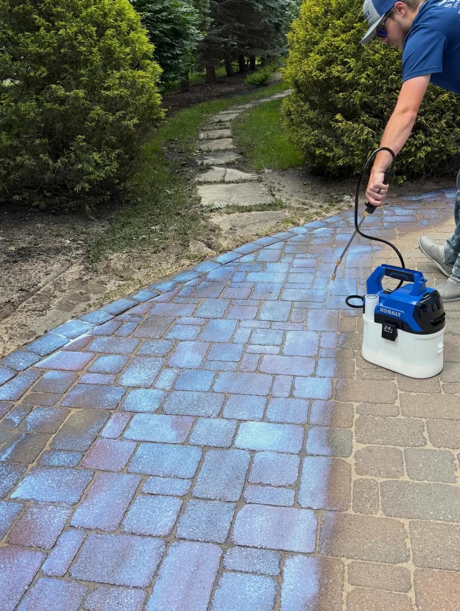 Professional-grade sealer being applied to a paver walkway, deepening the stone color
