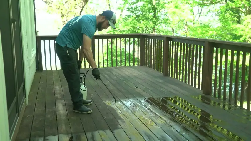 Six Mile crew member washing a wooden deck, clean boards emerging behind the spray