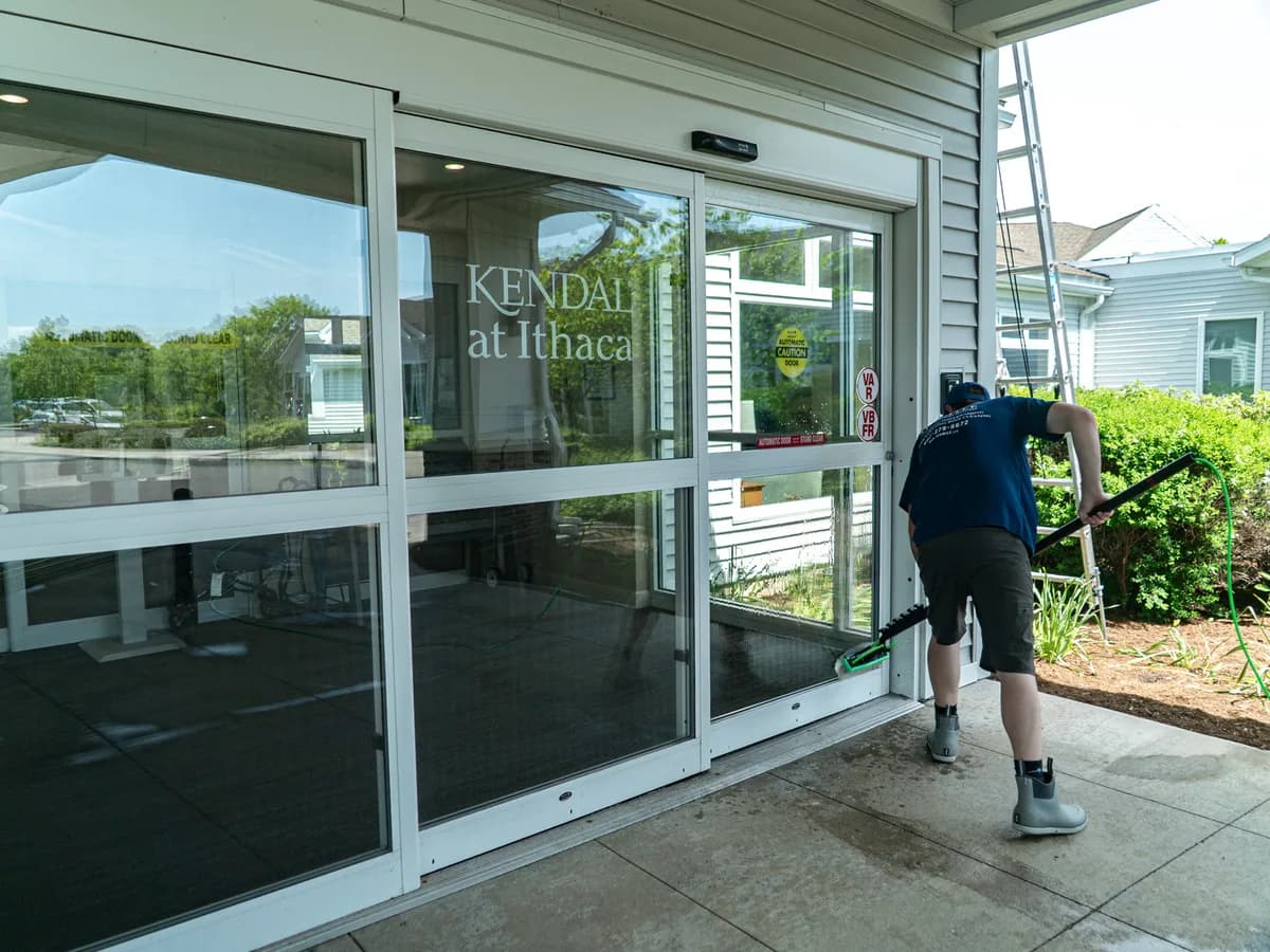 Six Mile crew member window cleaning the entrance at Kendal at Ithaca, a premier Ithaca senior living community