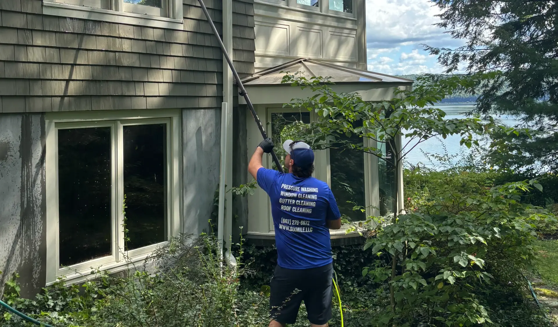 Six Mile crew member pure-water cleaning windows on a lakefront home